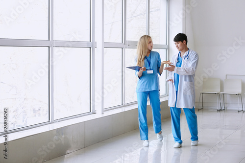 Male doctor and female medical assistant walking down the corridor in clinic