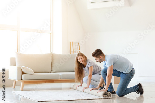Obraz na plátně Young couple unrolling carpet on floor
