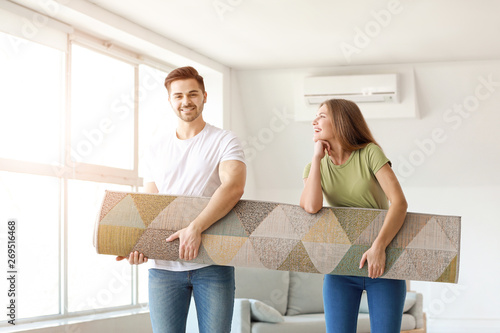 Young couple with carpet in new flat