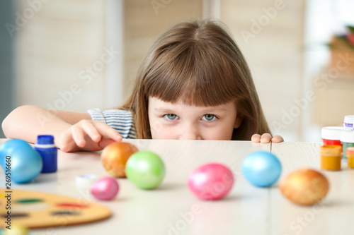 Cute little girl with painted Easter eggs at home