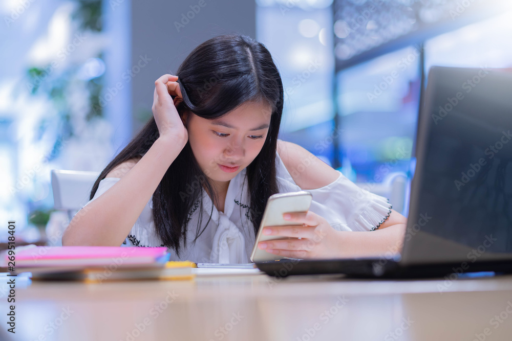 Portrait of young asian female student using her mobile phone sending a text outside at cafe. Portrait of young asian female student using her mobile phone sending a text outside at cafe.