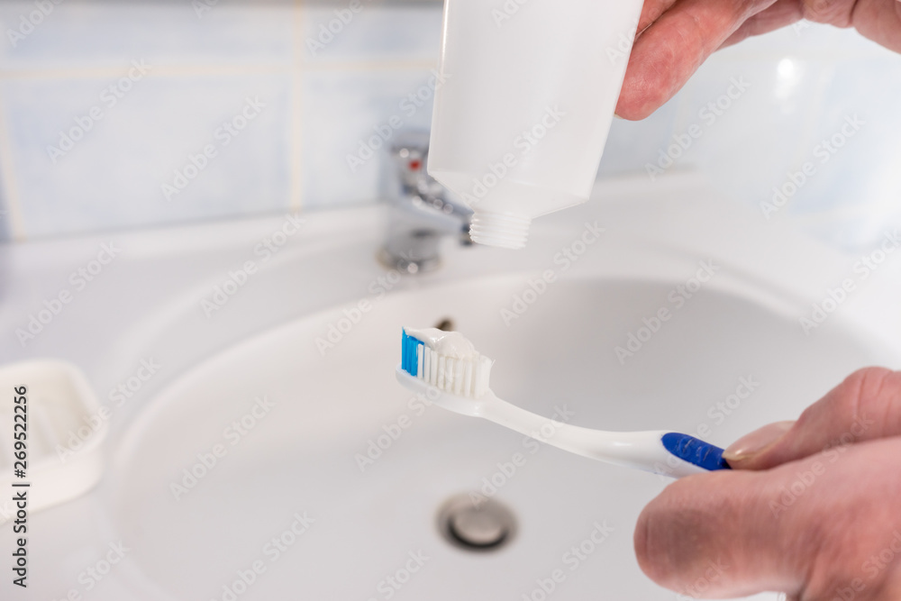 Person putting toothpaste on toothbrush Person putting toothpaste on toothbrush