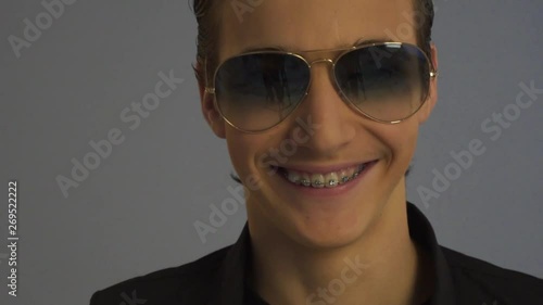 Smiling handsome boy in dark sunglasses . Cheerful teenager in stylish fashionable glasses. Close-up portrait of a young happy man in beautiful glasses. Handsome guy teen posing in the Studio.