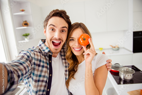 Close up photo pair beautiful amazing funky pair he him his macho she her lady hide eye fresh tomato just married honeymoon overjoyed make take selfies bonding apartments flat bright kitchen indoors