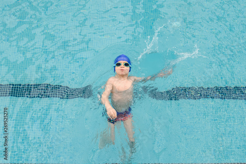 top view of a 7-year boy swimming backstroke in a swimming pool photo