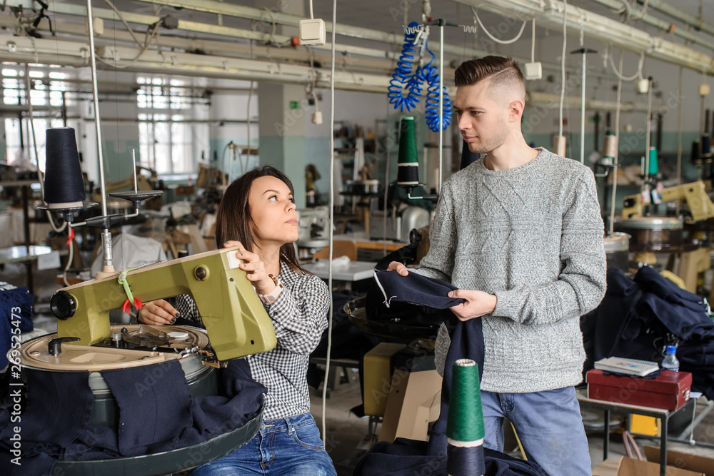 close up photo of a young man and a woman analyzing the work at the linking machine for knitting in textile industry