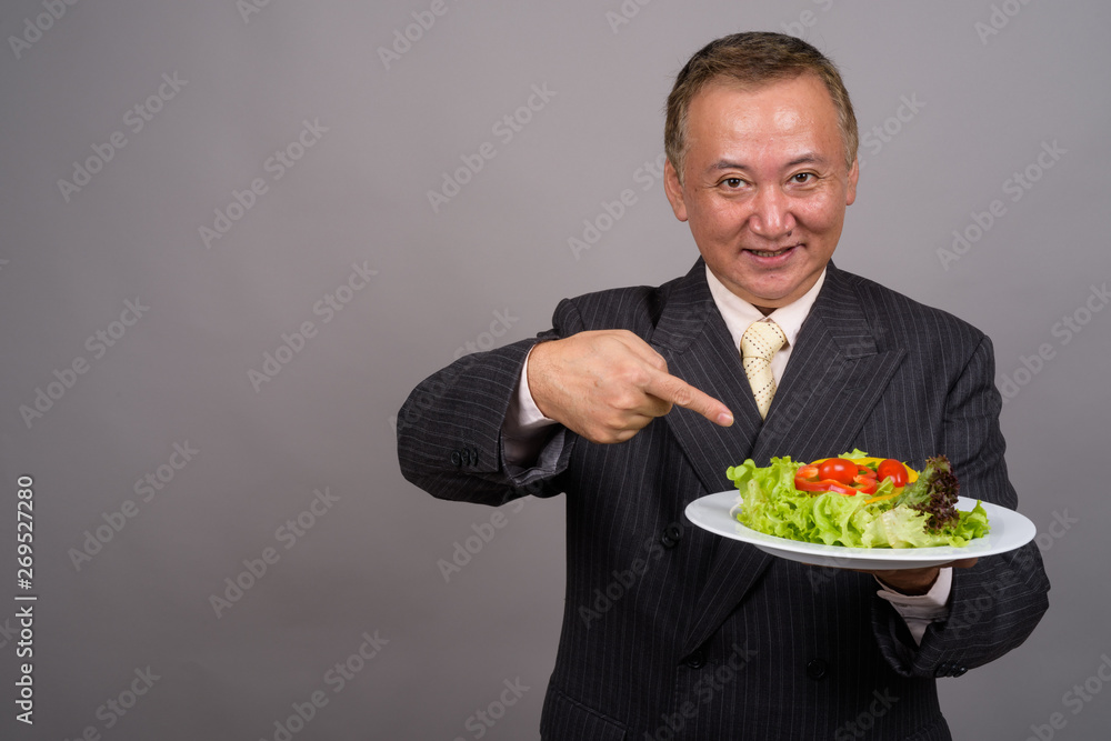 Portrait of mature Asian businessman against gray background Portrait of mature Asian businessman against gray background