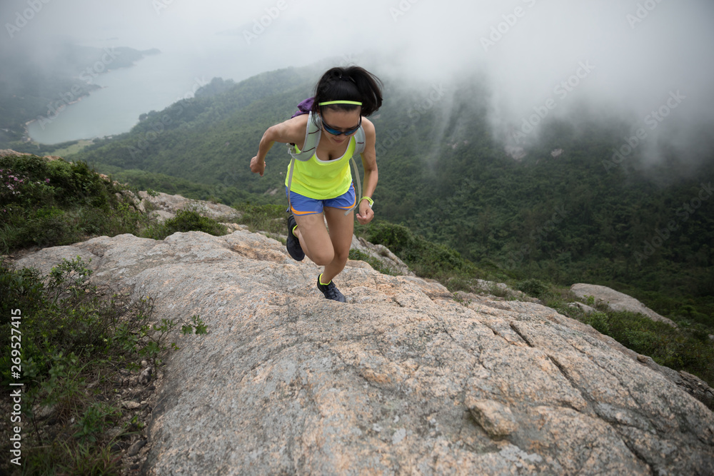 Young fitness woman running up at the seaside mountain top