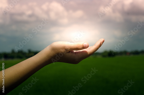 Light in the human hand on dark nature background.