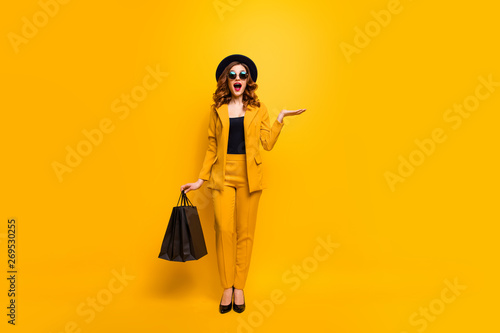 Full length body size photo beautiful crazy she her lady carry open palm clothes packs perfect look new low price sale discount wear specs formal-wear costume suit isolated yellow bright background