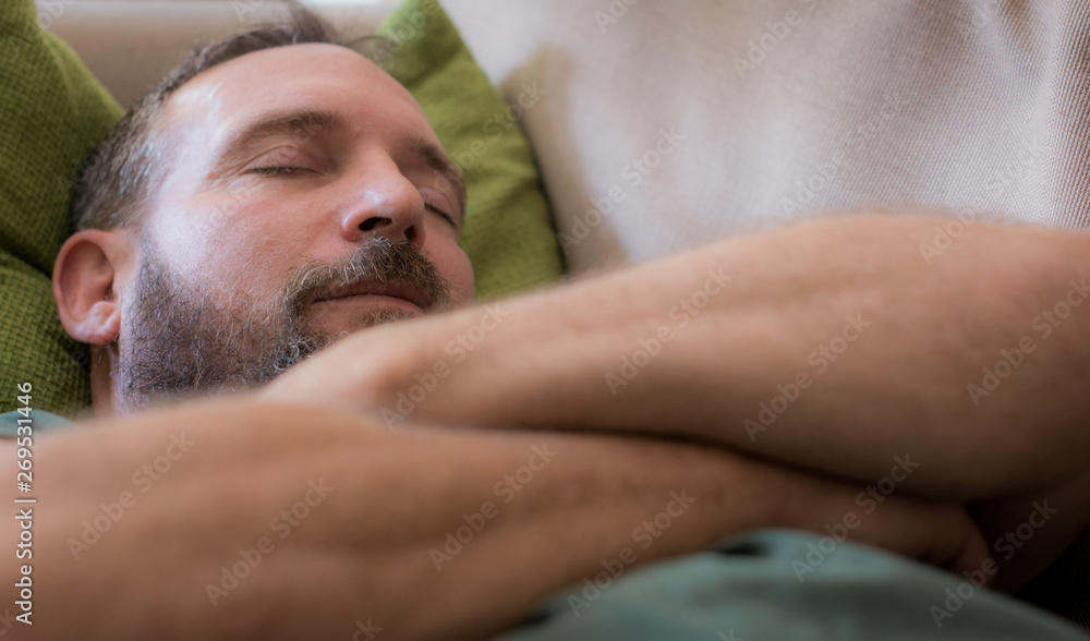 Fototapeta premium Middle-aged man having an afternoon nap on the couch