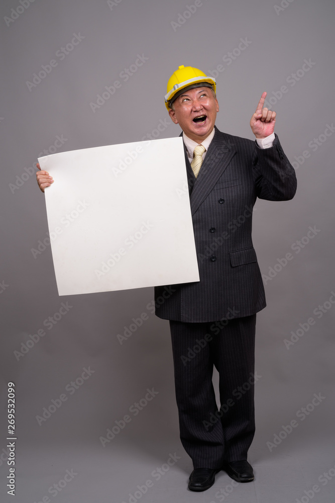 Mature Asian construction businessman against gray background Mature Asian construction businessman against gray background