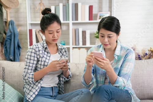 Картината върху платно group of young asian sisters obsessed with smartphones checking social networks at home