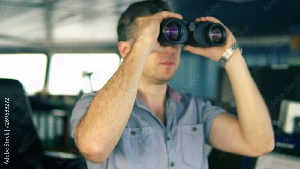 Navigational officer lookout on navigation watch looking through binoculars. Marine industry. COLREG collision regulations