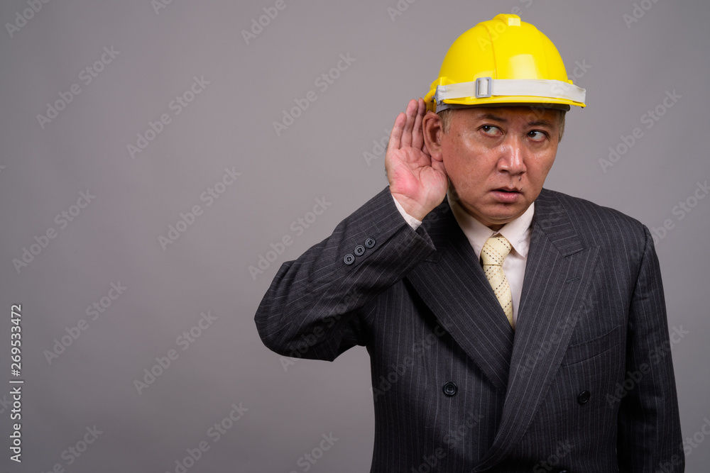 Mature Asian construction businessman against gray background Mature Asian construction businessman against gray background
