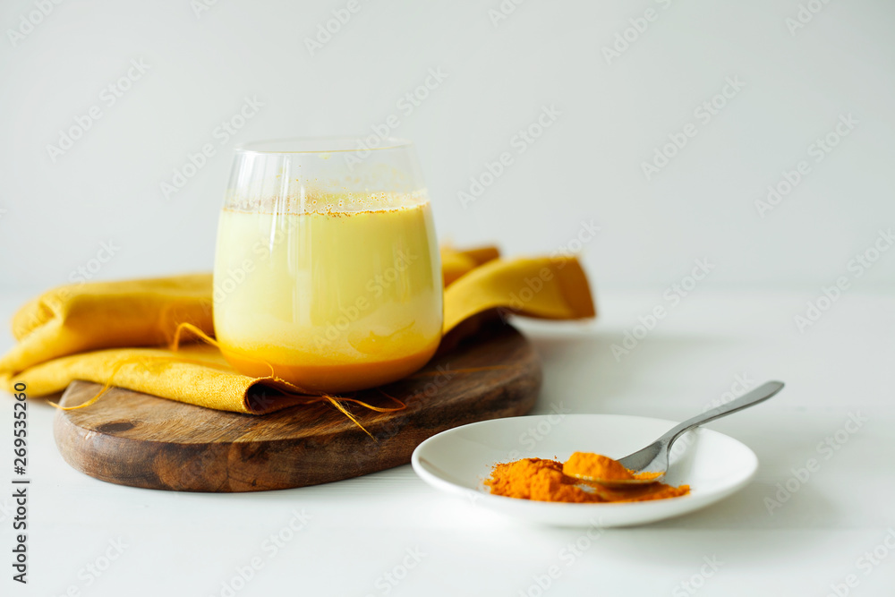 Healthy ayurvedic drink golden almond milk or pumpkin turmeric latte with curcuma powder on white background.Trendy Asian natural detox beverage with spices for vegans.Alternative medicine