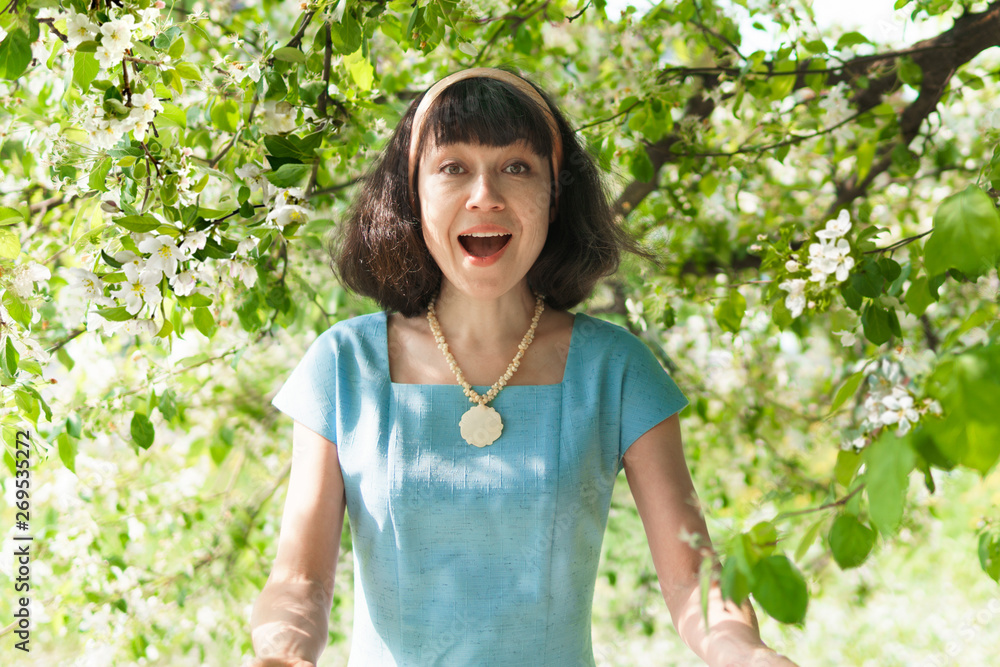 Beautiful woman in a long blue dress with flowering apple trees in the spring garden Beautiful woman in a long blue dress with flowering apple trees in the spring garden