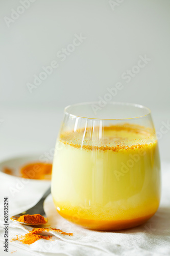 Healthy ayurvedic drink golden almond milk or pumpkin turmeric latte with curcuma powder on white background copy space.Trendy Asian natural detox beverage with spices for vegans.Alternative medicine
