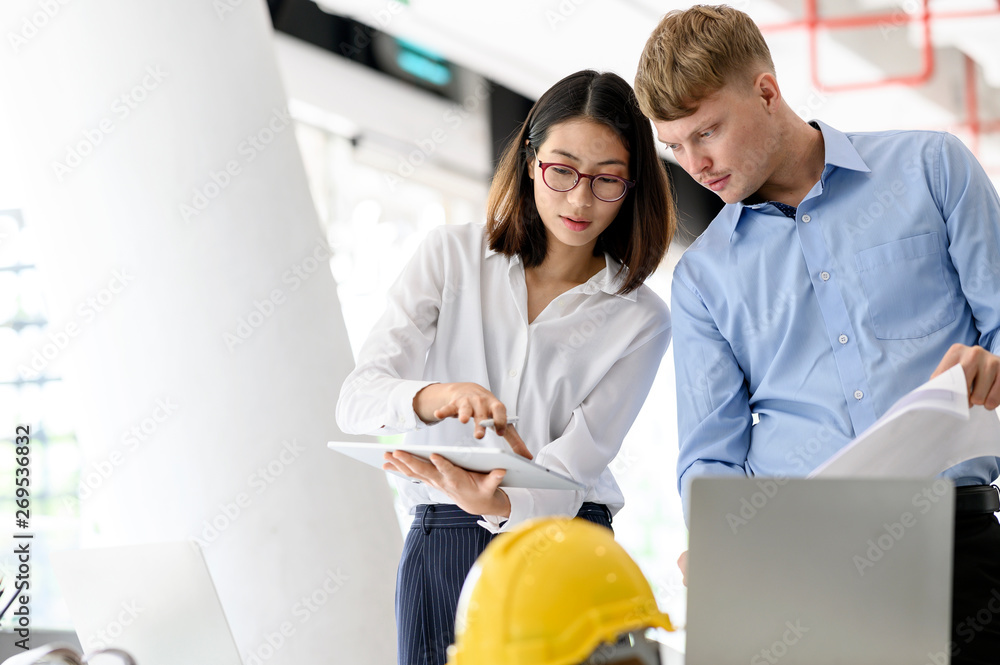 Obraz premium Architect designer engineer team colleagues working with blueprint and tablet in office.