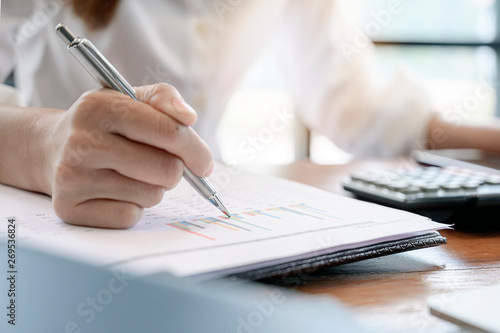 Closeup female hand holding pen pointing at paperwork.