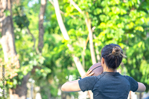 Asian Woman holding basketball Background blur tree in park. © Nueng