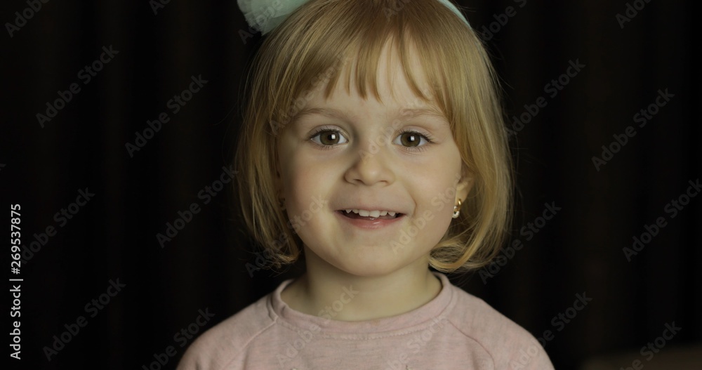 Close up of a little blonde cute girl face. Girl smiling. Inside. Portrait shot Close up of a little blonde cute girl face. Girl smiling. Inside. Portrait shot