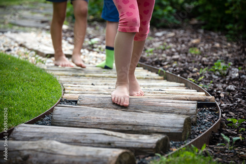Detail of kids legs walking on wooden pathway barefoot photo