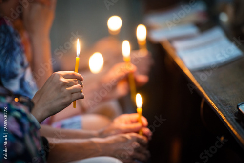 Religious people holding lit candles in church