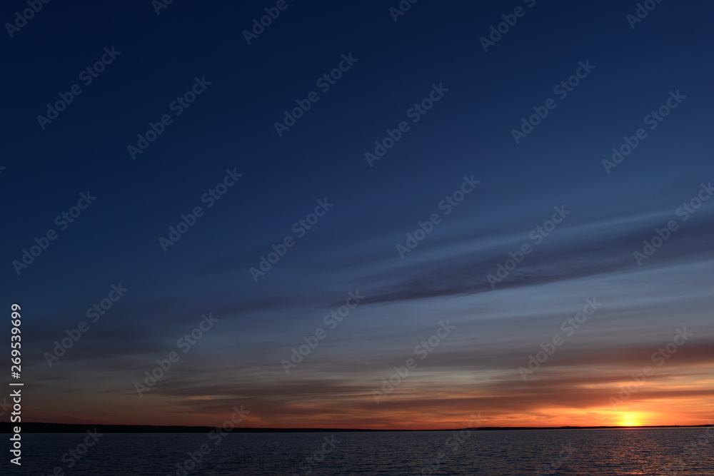 Twilight sky in the glow of sunset on the horizon above the water of the lake
