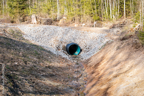 Culvert tube in the countryside. Ditch dug in the forest photo