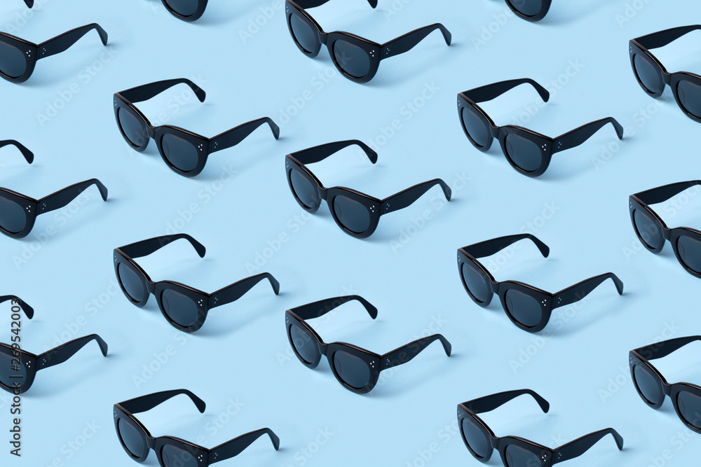 Fototapeta premium Black sunglasses pattern on pastel blue background.