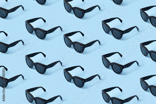 Black sunglasses pattern on pastel blue background.