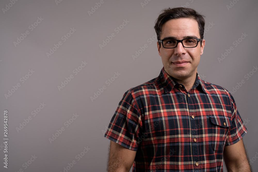 Handsome Persian man wearing eyeglasses against gray background Handsome Persian man wearing eyeglasses against gray background