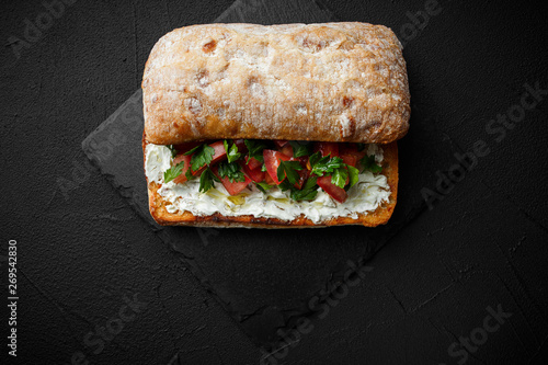 wholegraine ciabatta sandwich with sliced tomatoes, goat cheese, parsley. top view