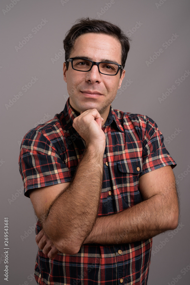 Handsome Persian man wearing eyeglasses against gray background Handsome Persian man wearing eyeglasses against gray background