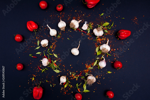 Chilli peppers, garlic, cherry tomatoes and spices on the black background. 