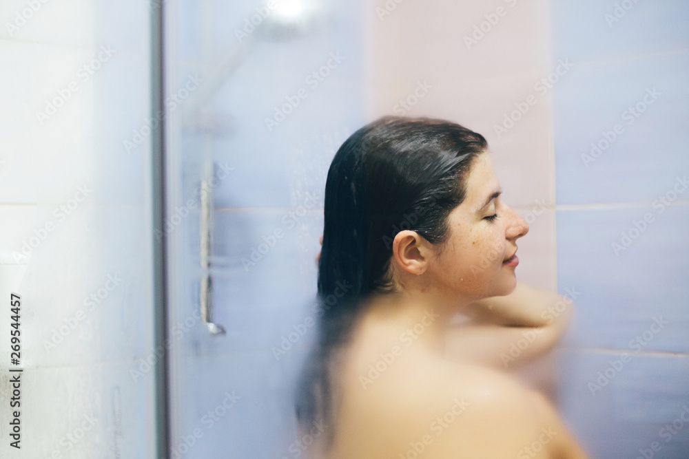 Beautiful woman taking shower in bathroom. Passionate girl sitting in bath.  Stock Photo