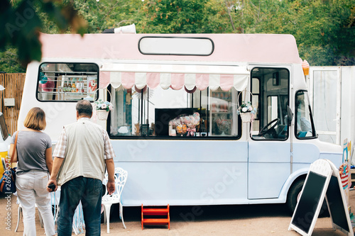 Food truck at summer street food festival in the city. Stylish retro food van truck with desserts, macaroons and ice cream. Summer market in the city. Space for text menu photo