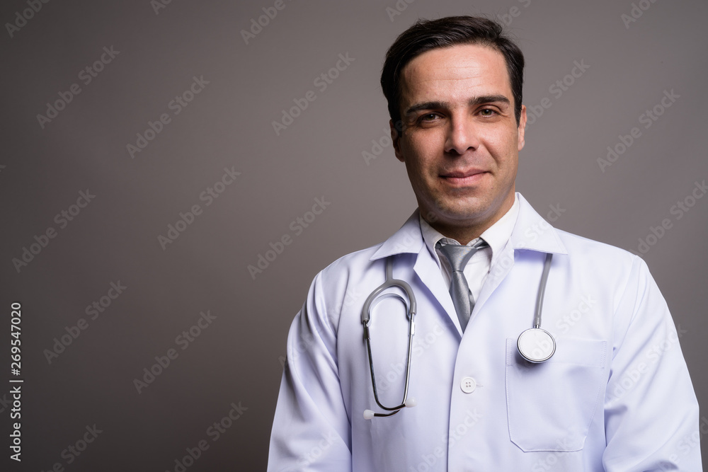 Handsome Persian man doctor against gray background Handsome Persian man doctor against gray background