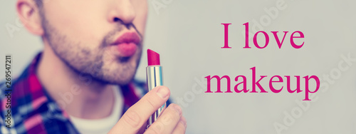 White metrosexual, man holding red lipstick in his hand close to face, on camera, lettering, I love makeup, front view, close up, photo