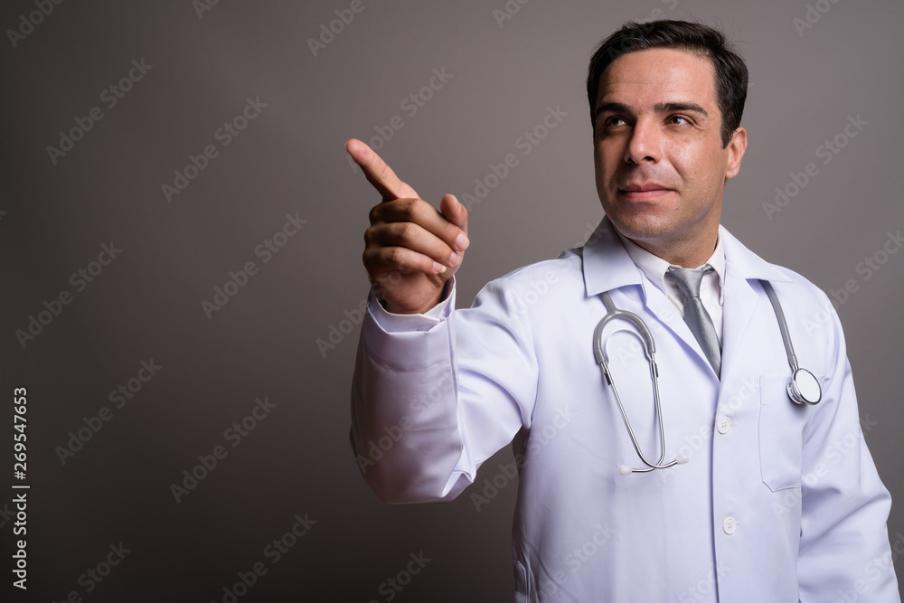 Handsome Persian man doctor against gray background Handsome Persian man doctor against gray background