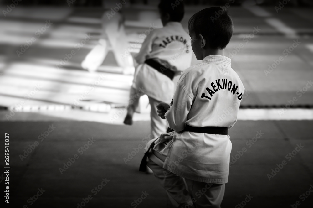 Martial arts. A young man in a white kimano with a green belt. Demonstrates Taekwondo Tuli. Black and white image for web and printing.