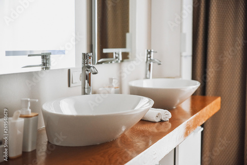 Modern stylish washbasins with chrome taps. Contemporary interior. Luxury lifestyle. Wood texture