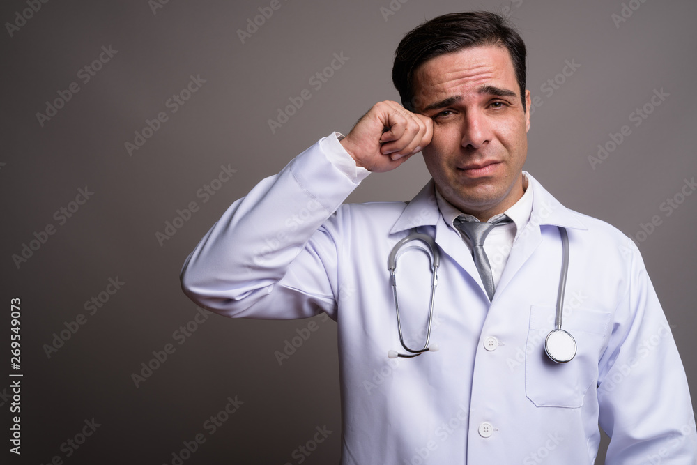 Handsome Persian man doctor against gray background Handsome Persian man doctor against gray background