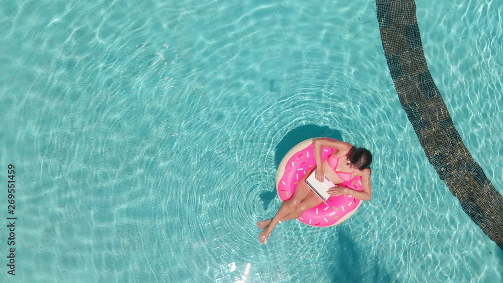 Beautiful woman and inflatable swim ring in shape of a donut in the pool.