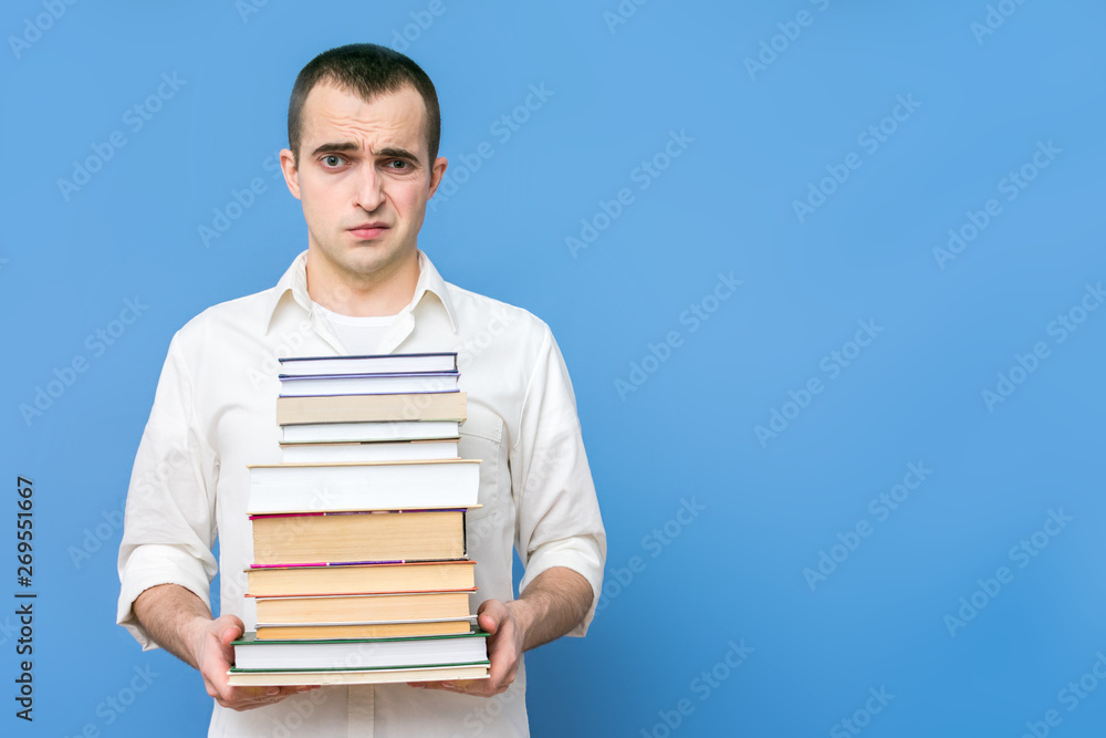 Tired student with books, the concept of heavy loads in education, blue background, copy space, for advertising, slogan Tired student with books, the concept of heavy loads in education, blue background, copy space, for advertising, slogan