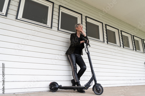 Frau mit e-Scooter an Hauswand in der Stadt
