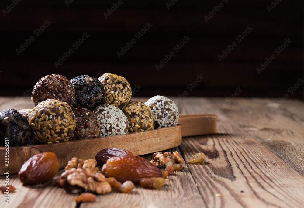 A group of energy balls lying on a wooden tray with a handle. Blurred wooden background. Organic natural food. A group of energy balls lying on a wooden tray with a handle. Blurred wooden background. Organic natural food.