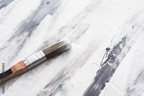repair and brush. brush in paint lying on the floor. black white paint strokes on plaster.