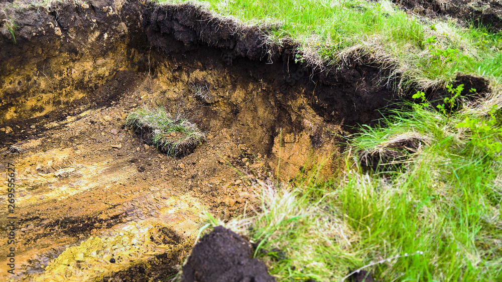Obraz premium muddy trench dug in brown soil with green grass on foreground